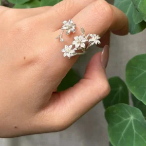 Matte-finish lily ring on a finger, showing textured petals and small buds