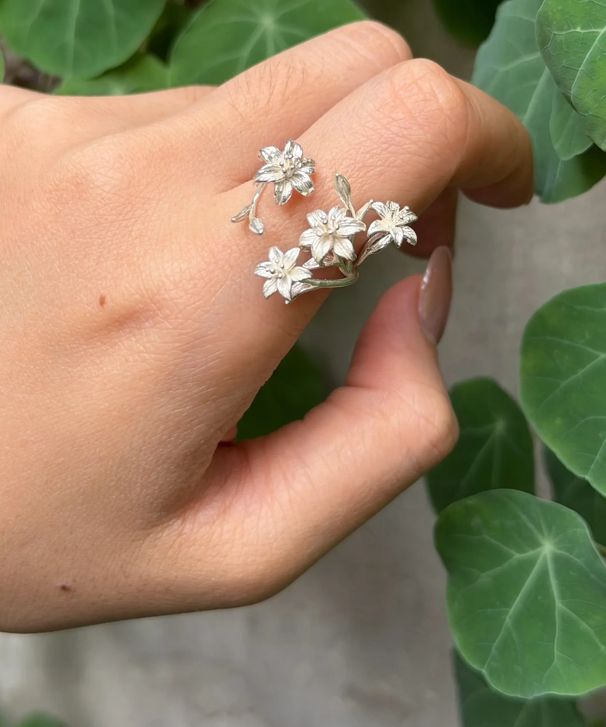 Matte-finish lily ring on a finger, showing textured petals and small buds