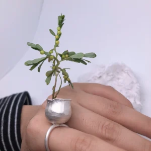 Close view of a small silver pot ring with an uneven rim and textured rounded walls
