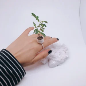 Silver flower pot ring viewed from above on a hand resting beside a white rock