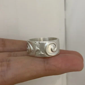 Rotated silver band showing the snail body and spiral shell beside curling lines.
