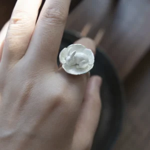 Thumbelina sterling silver rabbit ring worn on a hand, with a sleeping rabbit curled inside a flower.