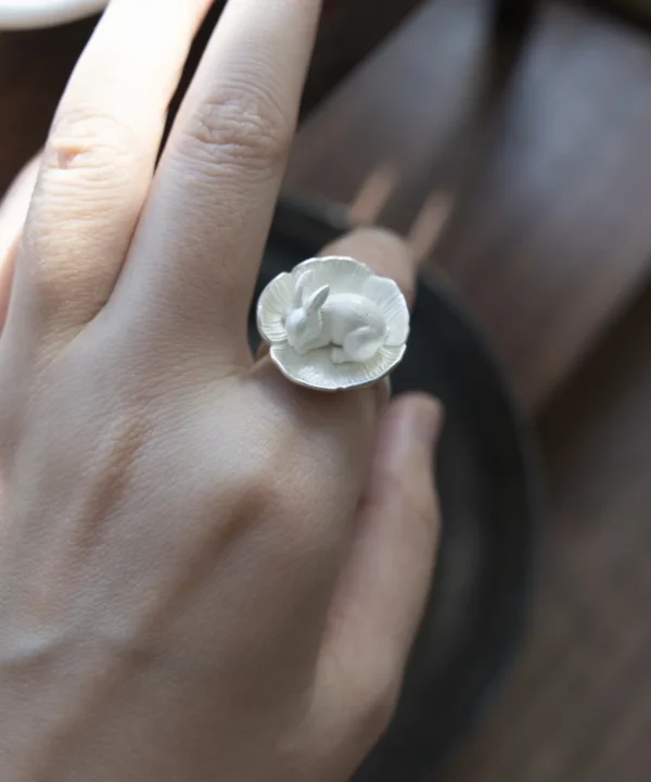 Thumbelina sterling silver rabbit ring worn on a hand, with a sleeping rabbit curled inside a flower.