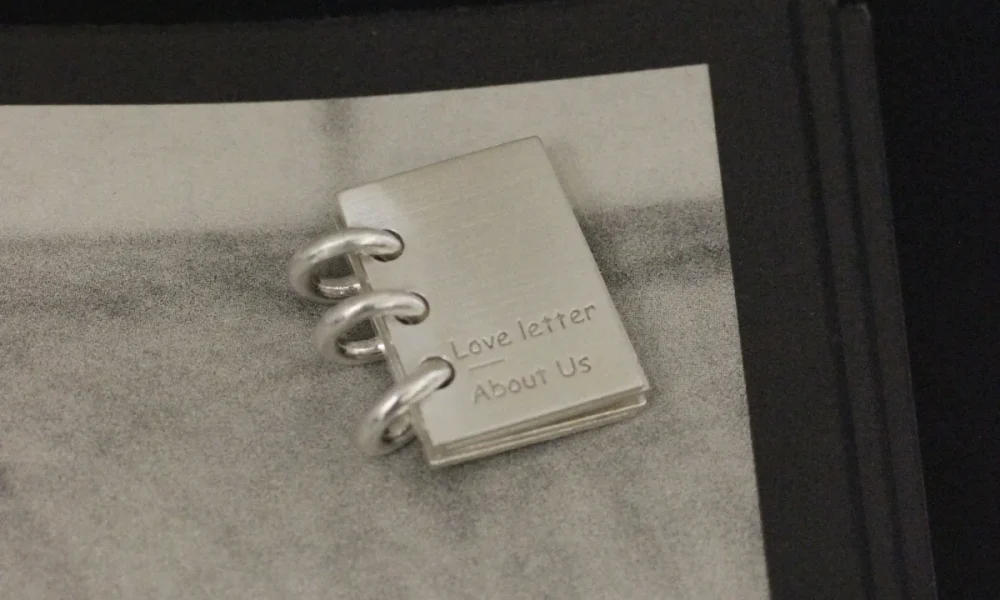 Lazesoul handmade 925 sterling silver book necklace featuring a miniature notebook‑style pendant engraved “Love Letter About Us,” with three binder rings, crafted as personalized custom jewelry for romantic keepsakes and meaningful gifts.